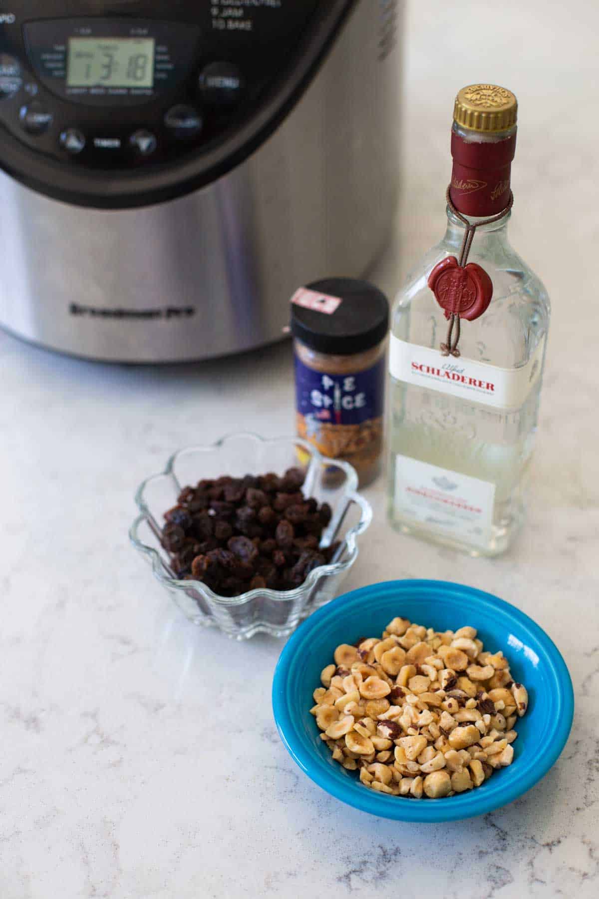 Chopped hazelnuts, raisins, kirsch, and spices sit in front of a bread maker.