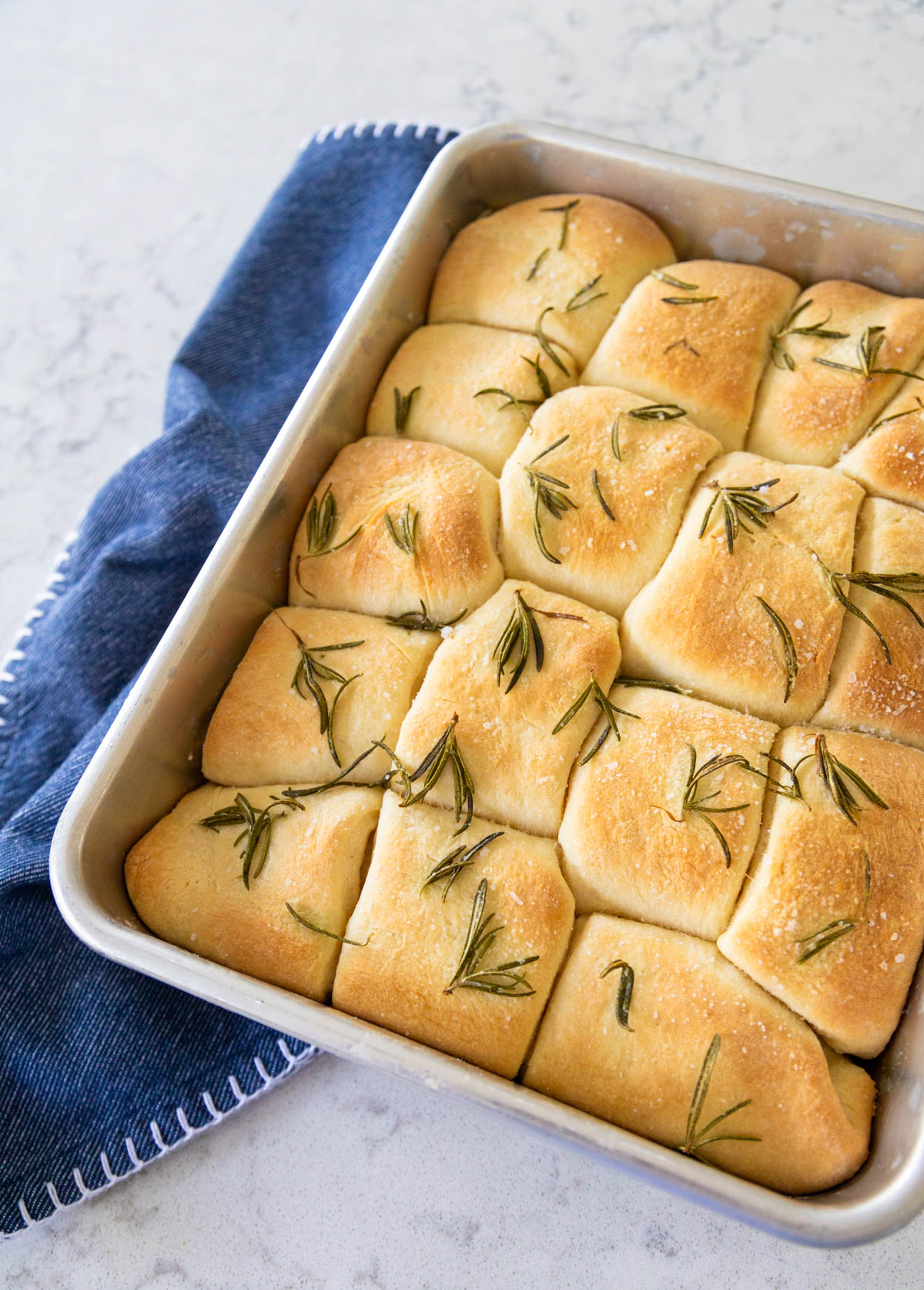 The dinner rolls have just come out of the oven and are a gorgeous golden brown with roasted rosemary leaves on top.