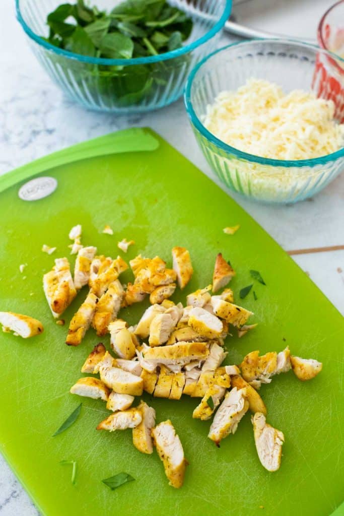 A green cutting board has chopped chicken tenderloins that have been baked in the airfryer.