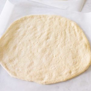 Pizza dough from the bread machine has been rolled out into a circle and is ready for toppings.