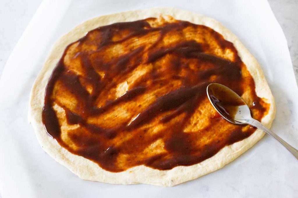 Step 1: Spread barbecue sauce over the pizza dough with the backside of a spoon.