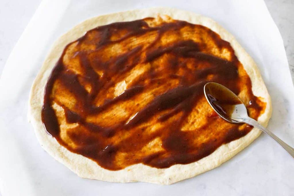 Step 1: Spread barbecue sauce over the pizza dough with the backside of a spoon.