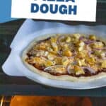 A homemade pizza is ready to go into the hot oven that has a pizza stone inside.