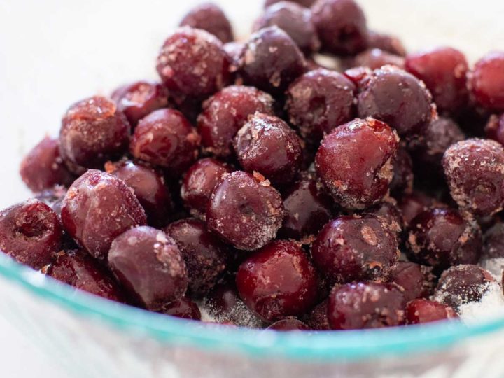 A mixing bowl filled with pitted, frozen cherries.