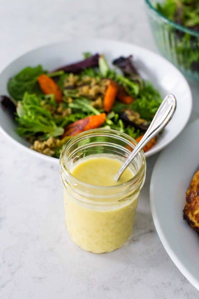 Lemon parmesan vinaigrette is in a jar ready to dress a salad.