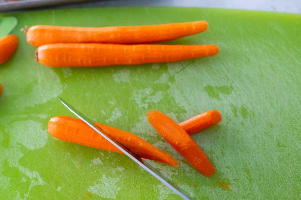 A knife is showing how to cut through the carrots at an angle.