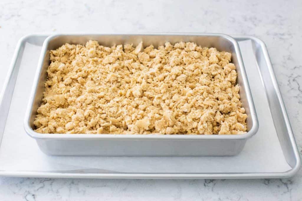 The assembled cherry crisp is ready for the oven and sits on a baking sheet lined with parchment paper.