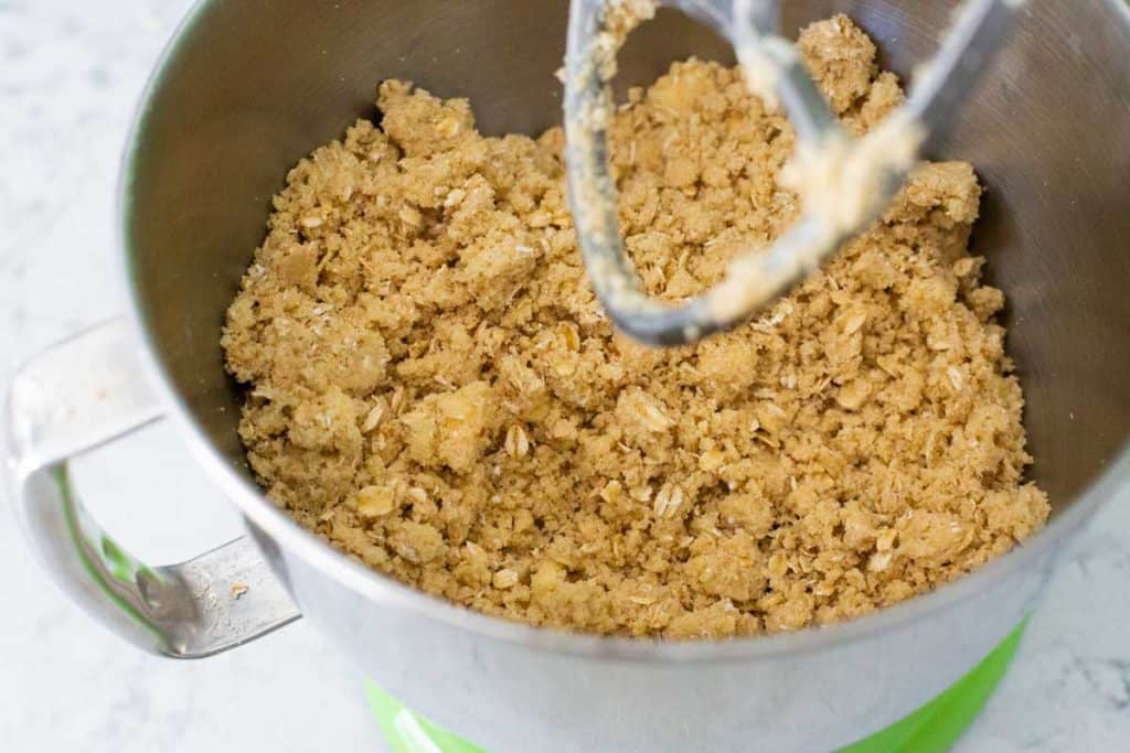 The finished cherry crisp topping is in the bowl of the stand mixer and shows how it is clumping together.