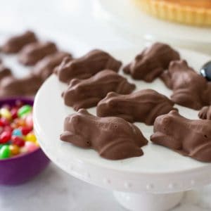 A cake plate has a serving of Harry Potter chocolate frogs next to a bowl of jelly beans.