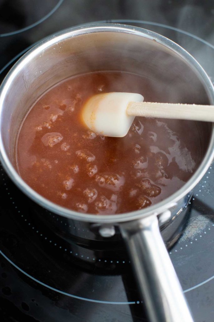 A saucepan is cooking the sweet and sour sauce.