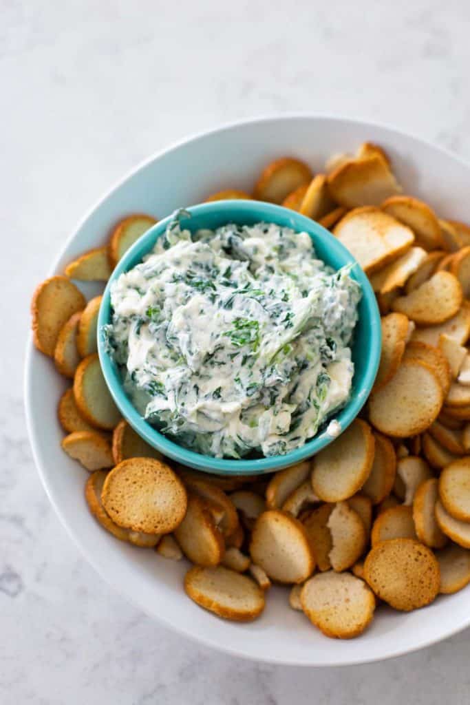 The finished spinach dip is ready for serving with bagel chips on the side.