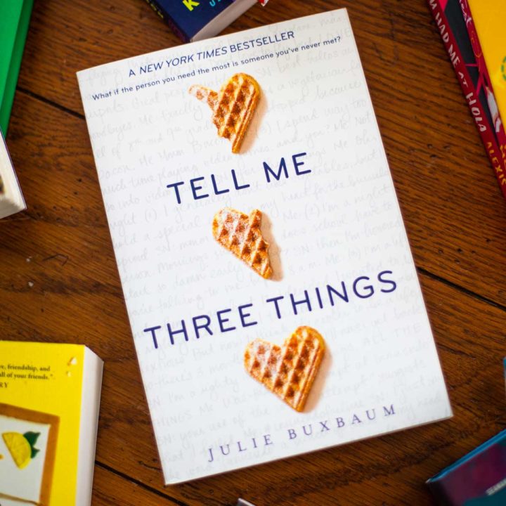 A copy of Tell Me Three Things sits on a table.