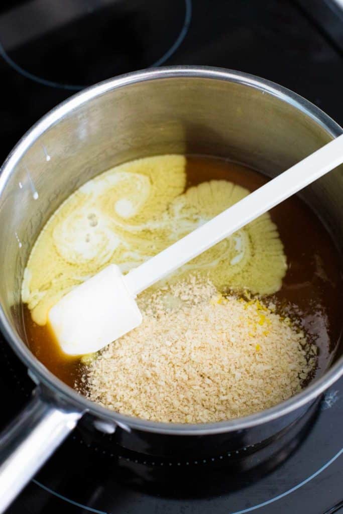 The bread crumbs and butter have been added to the golden syrup in the pan.