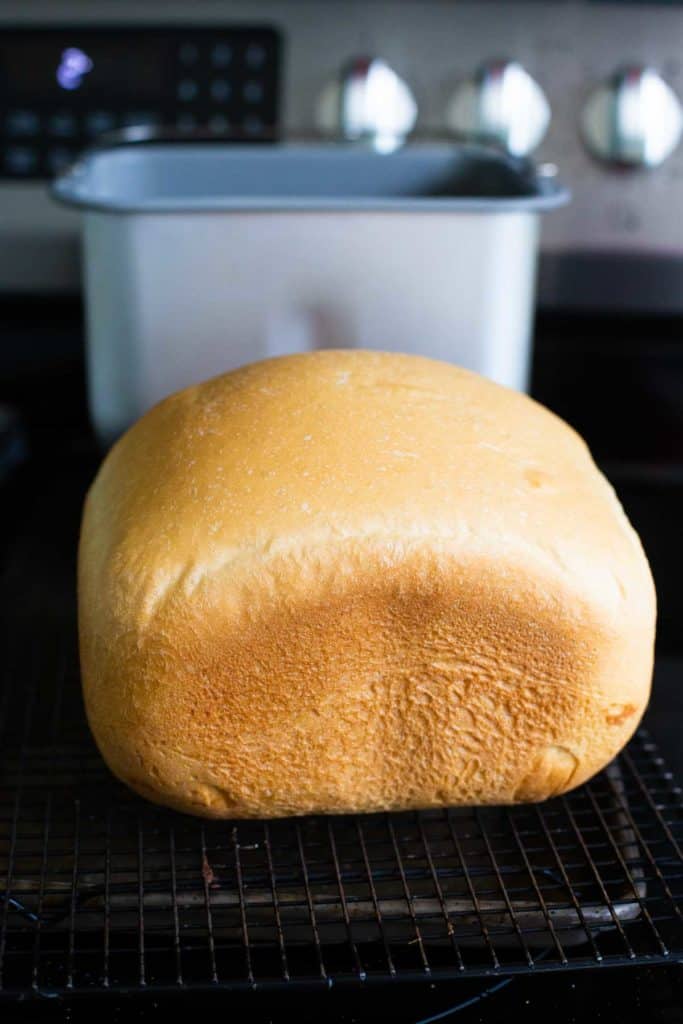 The baked Italian bread sits in front of the bread machine pan.