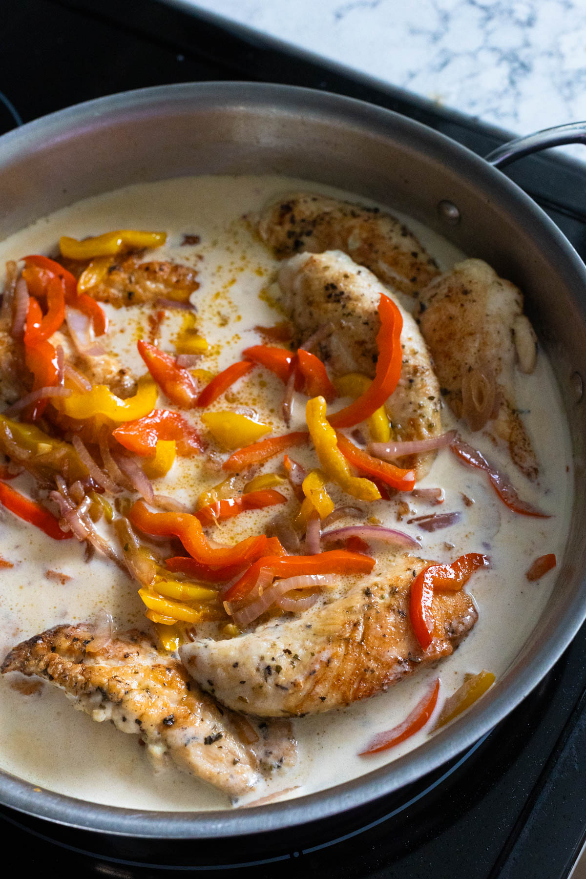 The chicken and peppers have been added back into the skillet in the cream sauce to warm through.