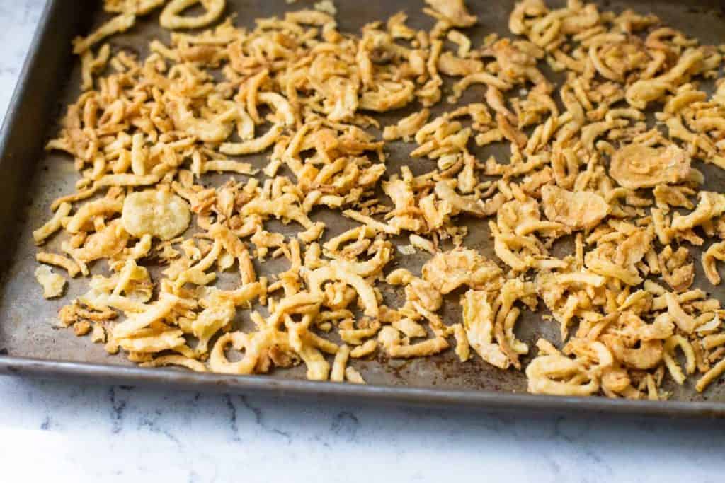 Fried onions are spread on a baking sheet for the oven.