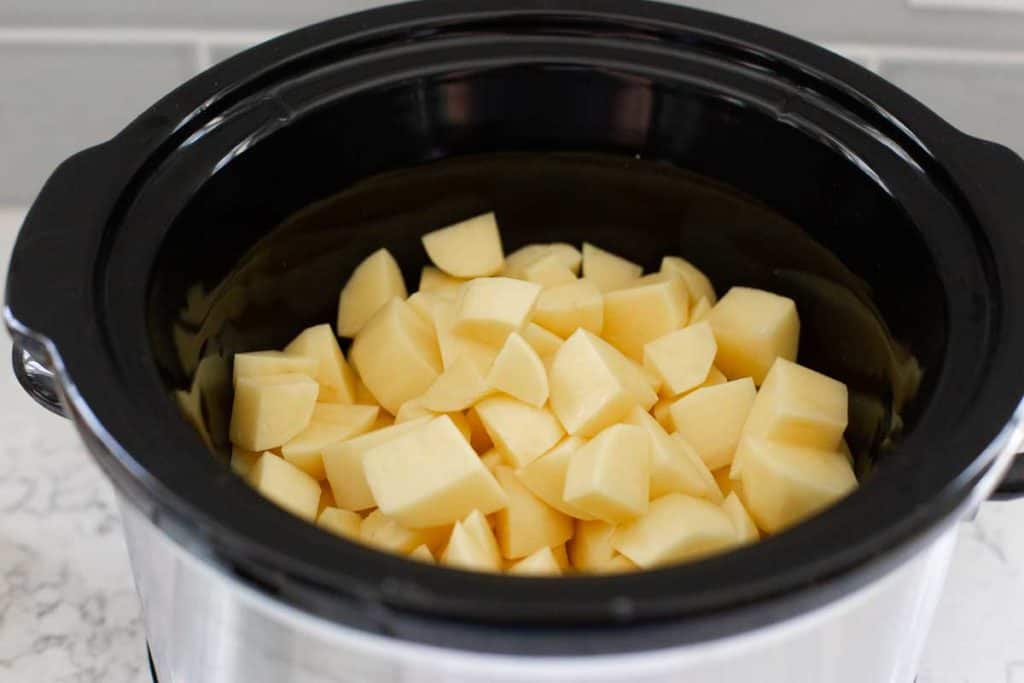 Chopped potatoes are in a Crockpot waiting to be cooked.