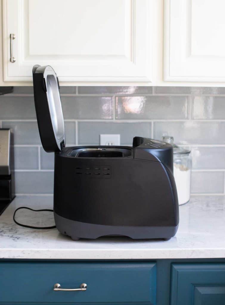 The Hamilton Beach bread machine has the lid open and is turned to the side to show the profile of the dimensions.