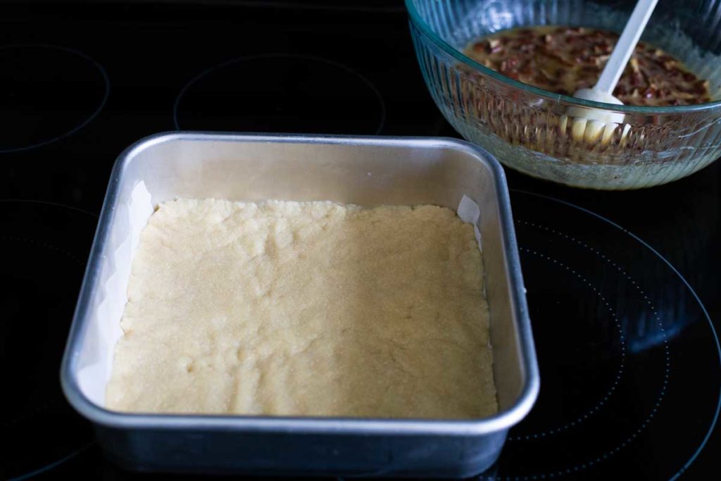 The shortbread crust gets pre-baked in the oven and will now be filled with pecan filling.