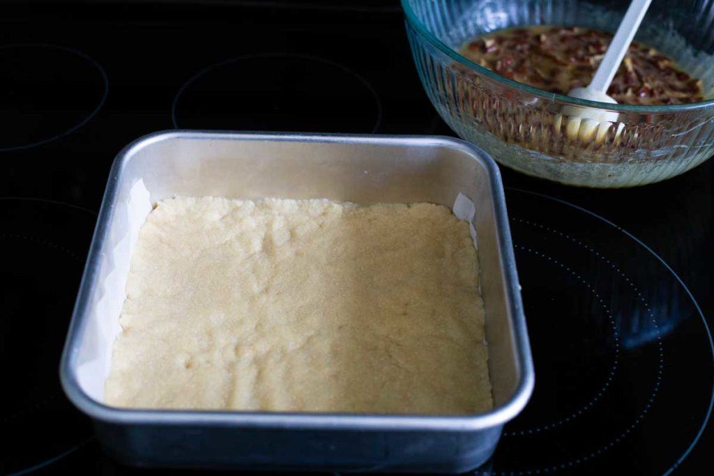 The shortbread crust gets pre-baked in the oven and will now be filled with pecan filling.