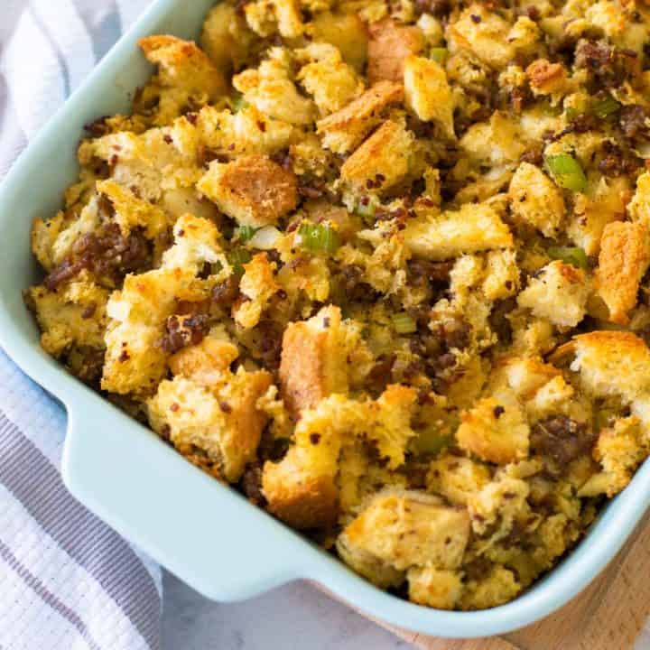 A baking dish filled with homemade sausage stuffing sits next to a striped towel.