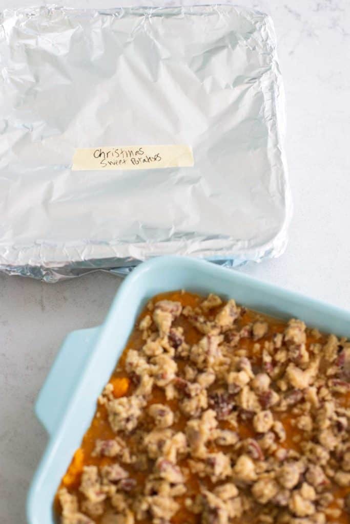 A pan of sweet potato casserole is ready for the oven, another one has been covered in aluminum foil for the freezer.