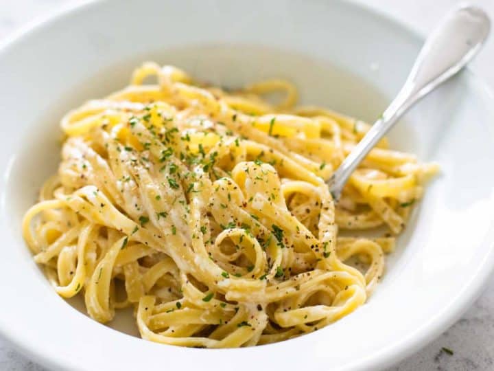 A plate of spaghetti coated in homemade alfredo sauce sprinkled with parmesan cheese.