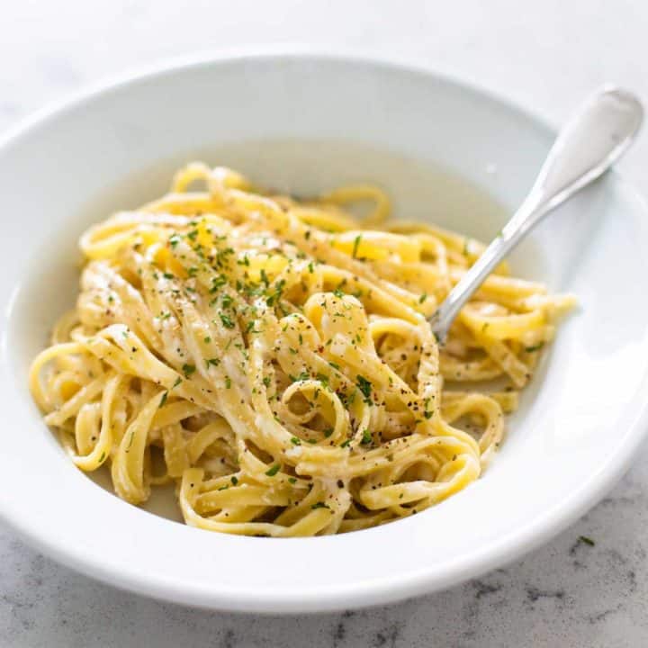 A plate of spaghetti coated in homemade alfredo sauce sprinkled with parmesan cheese.