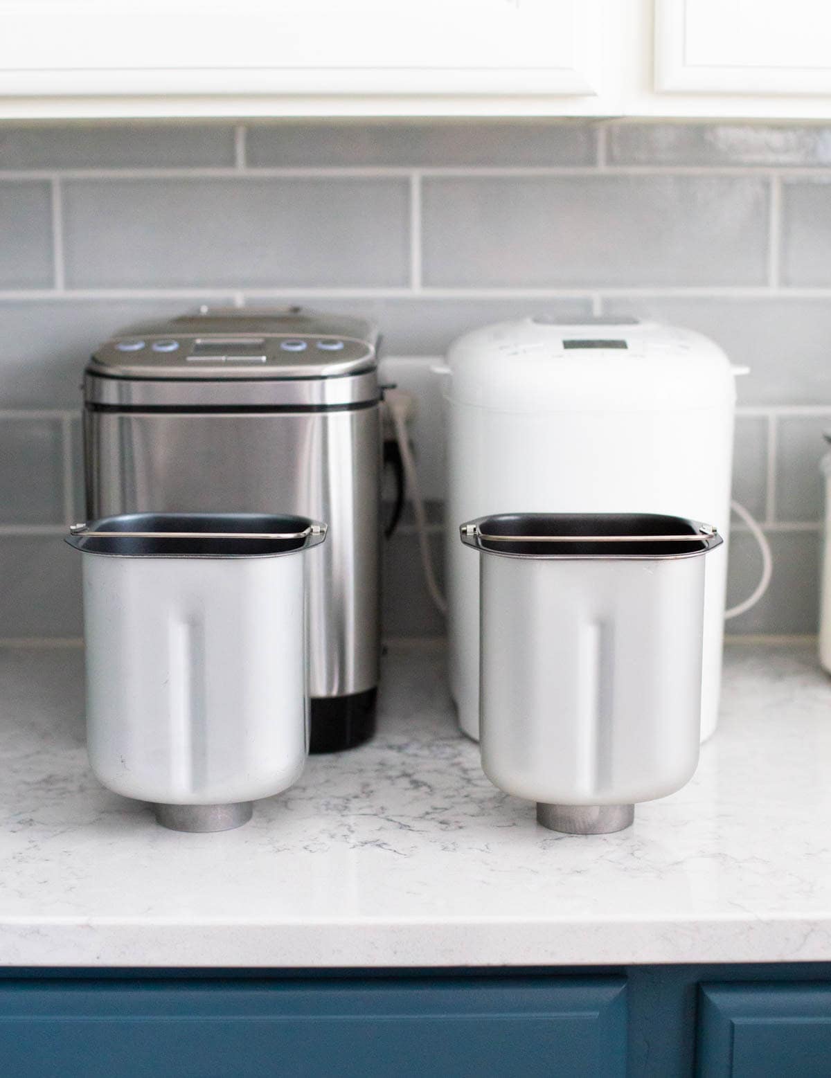 The bread pans for each of the Cuisinart and Amazon Basics are sitting on the counter directly in front of their paired machine.