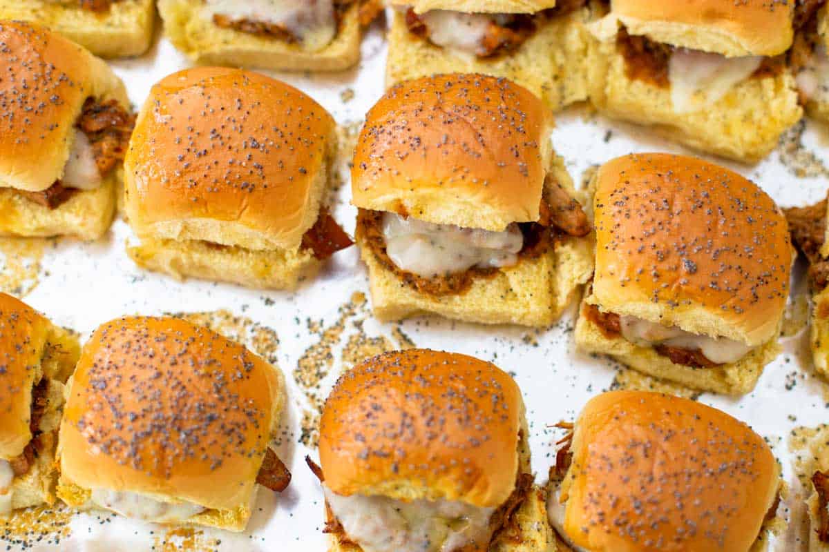 The finished baked BBQ chicken sliders are on a baking tray.