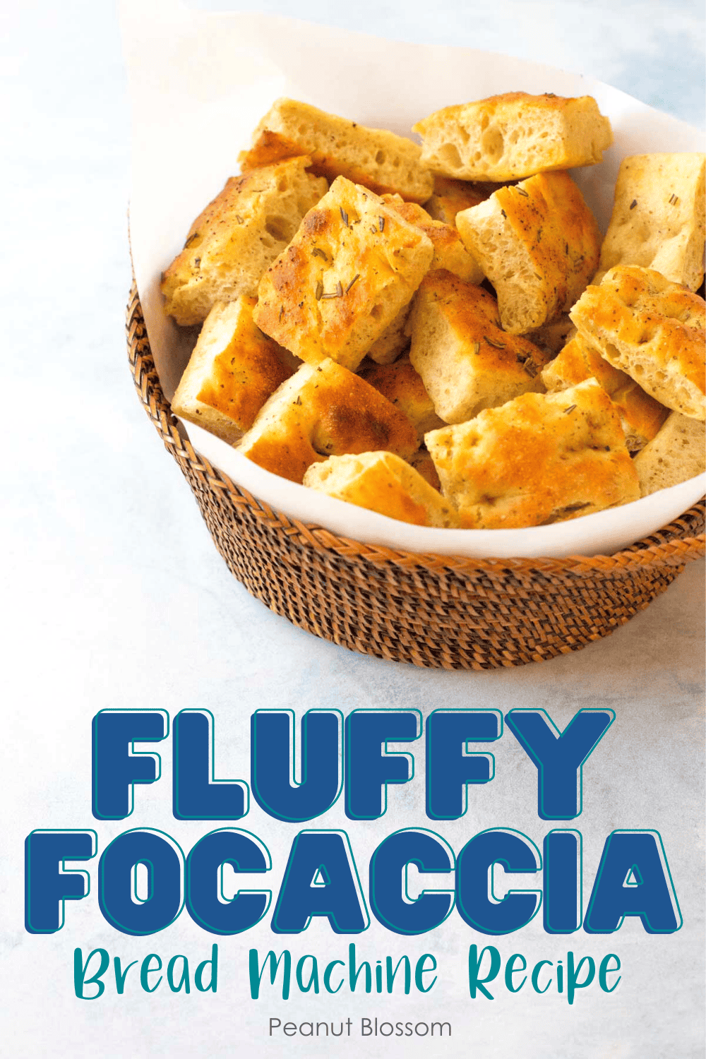 A woven bread basket lined with parchment paper holds cut squares of baked focaccia bread. 