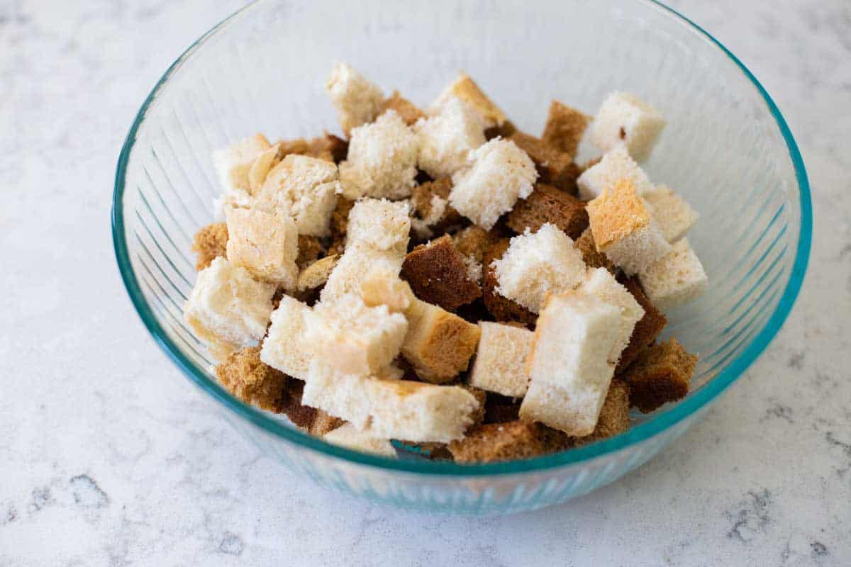 A mixing bowl shows a variety of bread being used to make croutons.