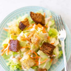 A simple green salad is topped with shredded croutons and homemade croutons made from bread machine bread.