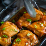 The chicken thighs are fresh out of the oven and ready to be served with green onions on top.