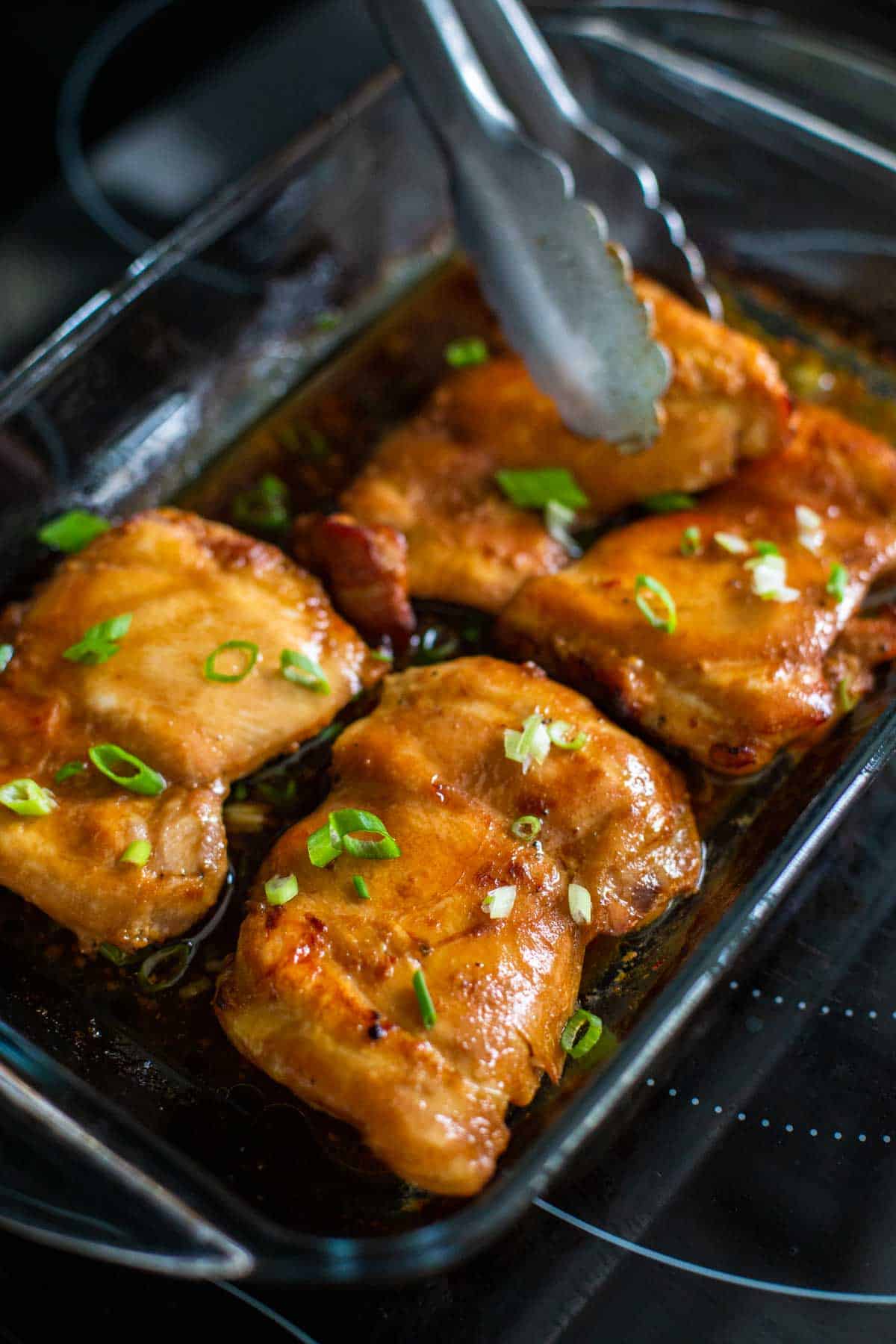 The chicken thighs are fresh out of the oven and ready to be served with green onions on top.