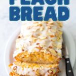 The sliced loaf of peach bread shows the drizzled glaze and toasted almonds on top.