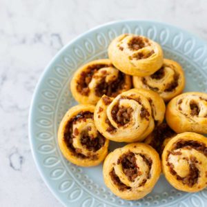 A platter of sausage swirl appetizers is ready to be served.