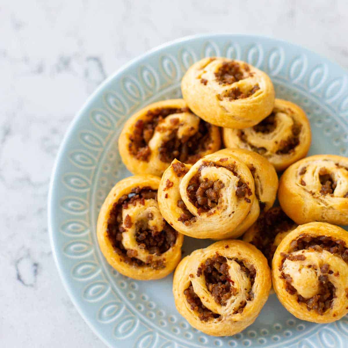 A platter of sausage swirl appetizers is ready to be served.