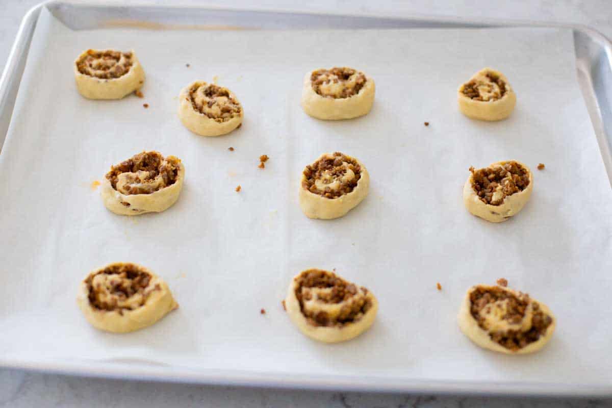 A baking sheet lined with parchment has prepped sausage swirls ready for baking.