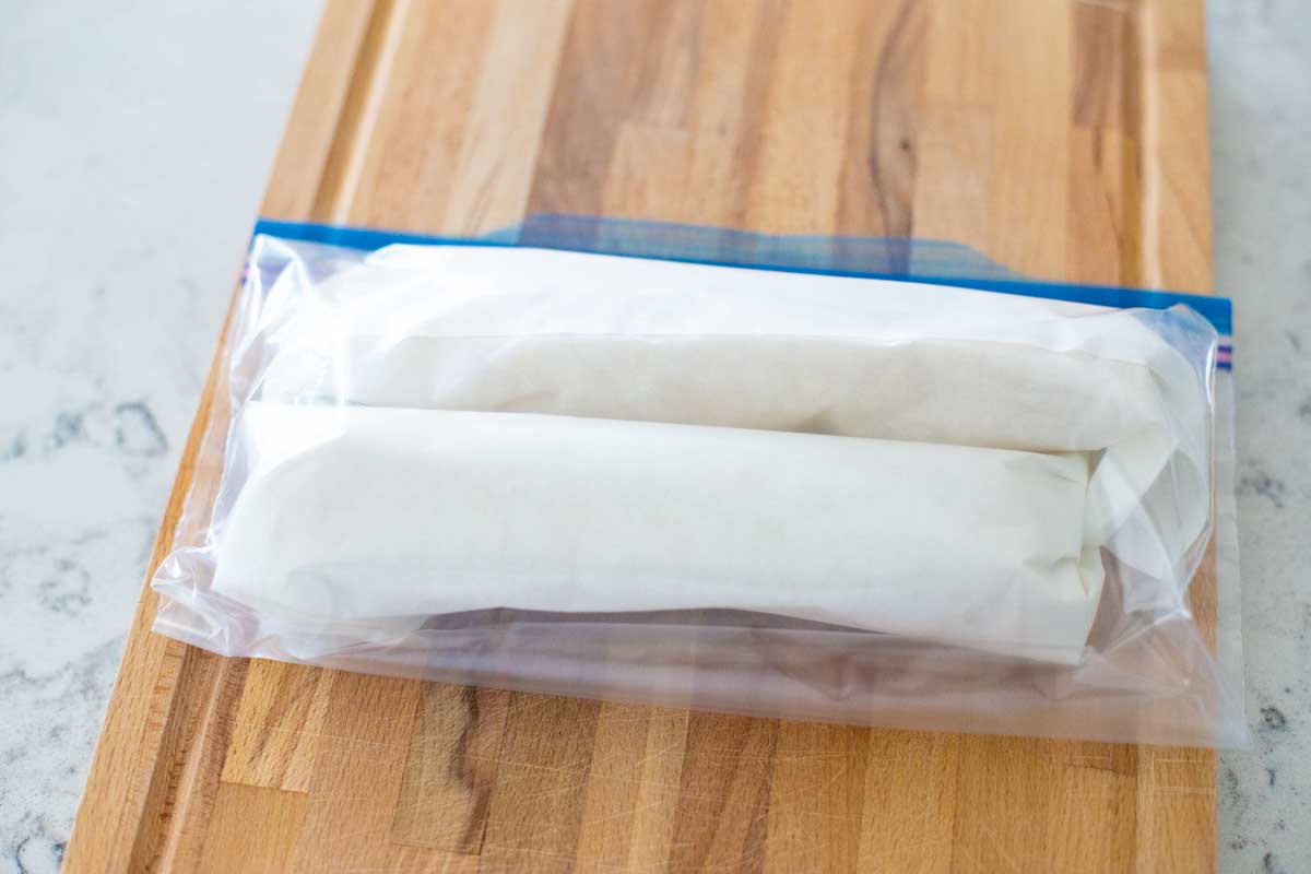 Two rolls of sausage swirls are wrapped in parchment and ready for the freezer.