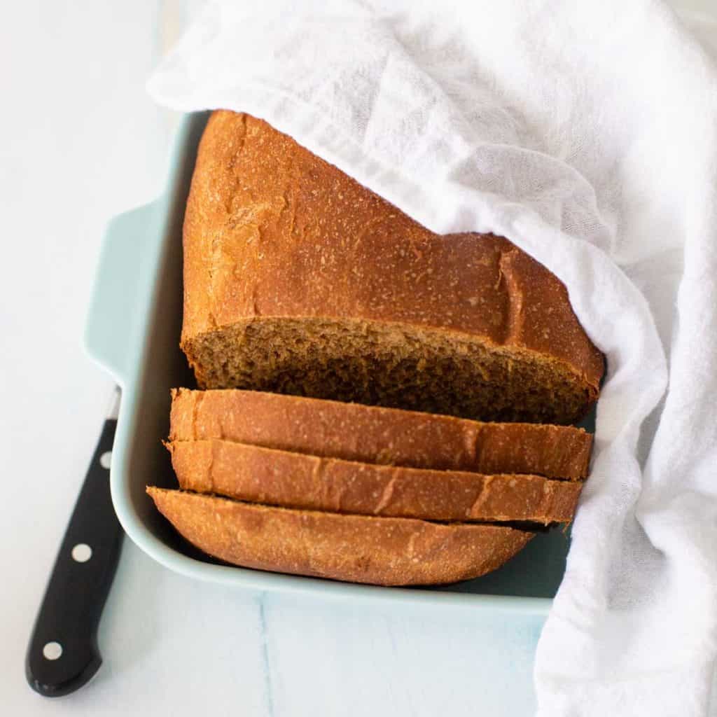 The steakhouse brown bread sits in a dish covered by a napkin with a knife on the side.