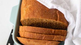 The steakhouse brown bread sits in a dish covered by a napkin with a knife on the side.