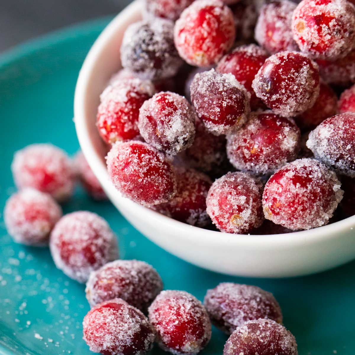 A close-up photo of sugared cranberries show the red fruits and sparkling sugar coating.
