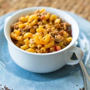 A serving of turkey taco mac is in a bowl on a plate with a spoon.