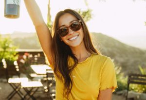 A young woman wearing sunglasses and a yellow shirt.