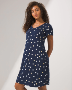 A woman is wearing a navy blue nightgown with polka dots.