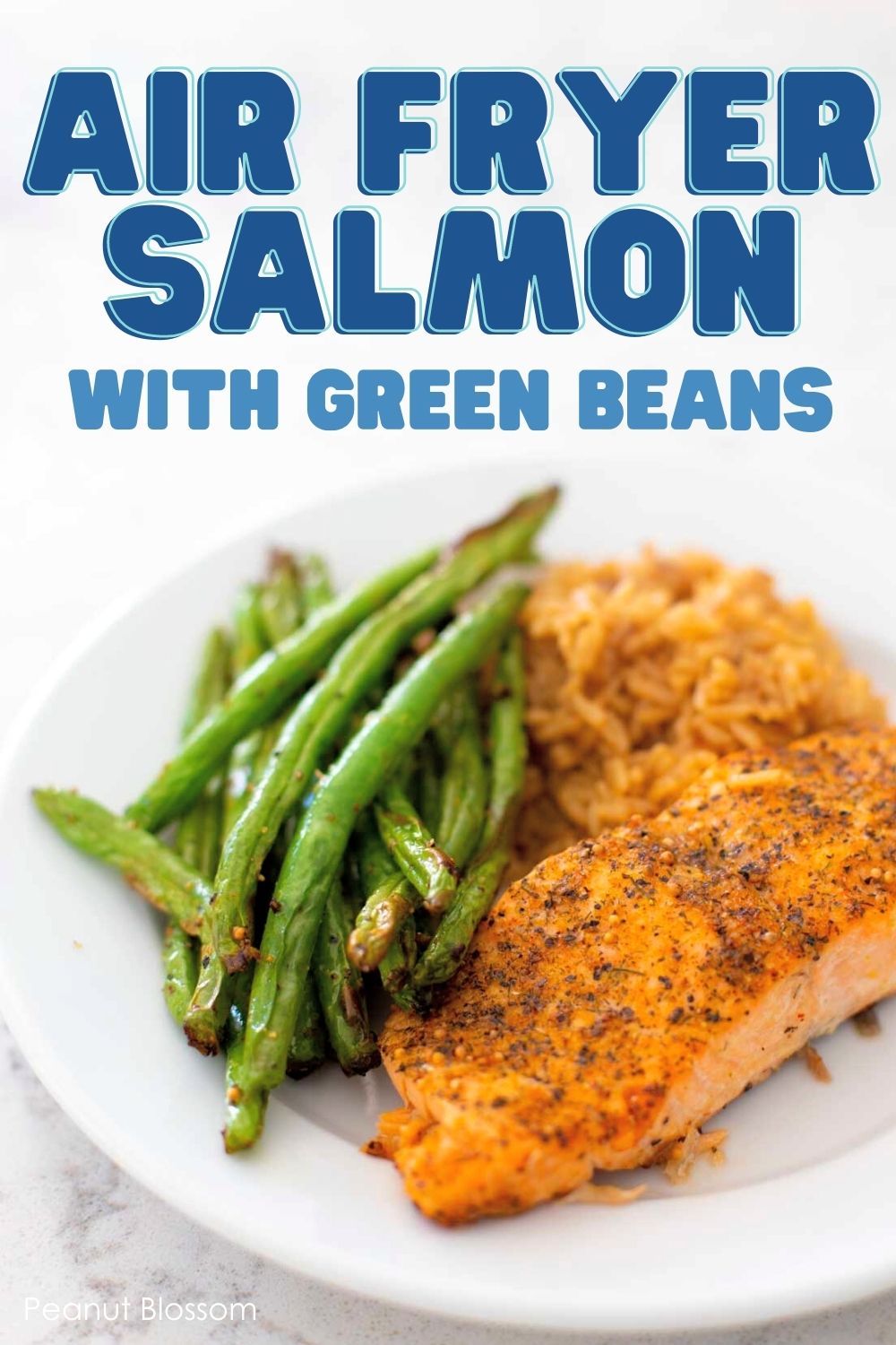 The cooked salmon sits on a plate next to air fryer green beans and a scoop of rice.