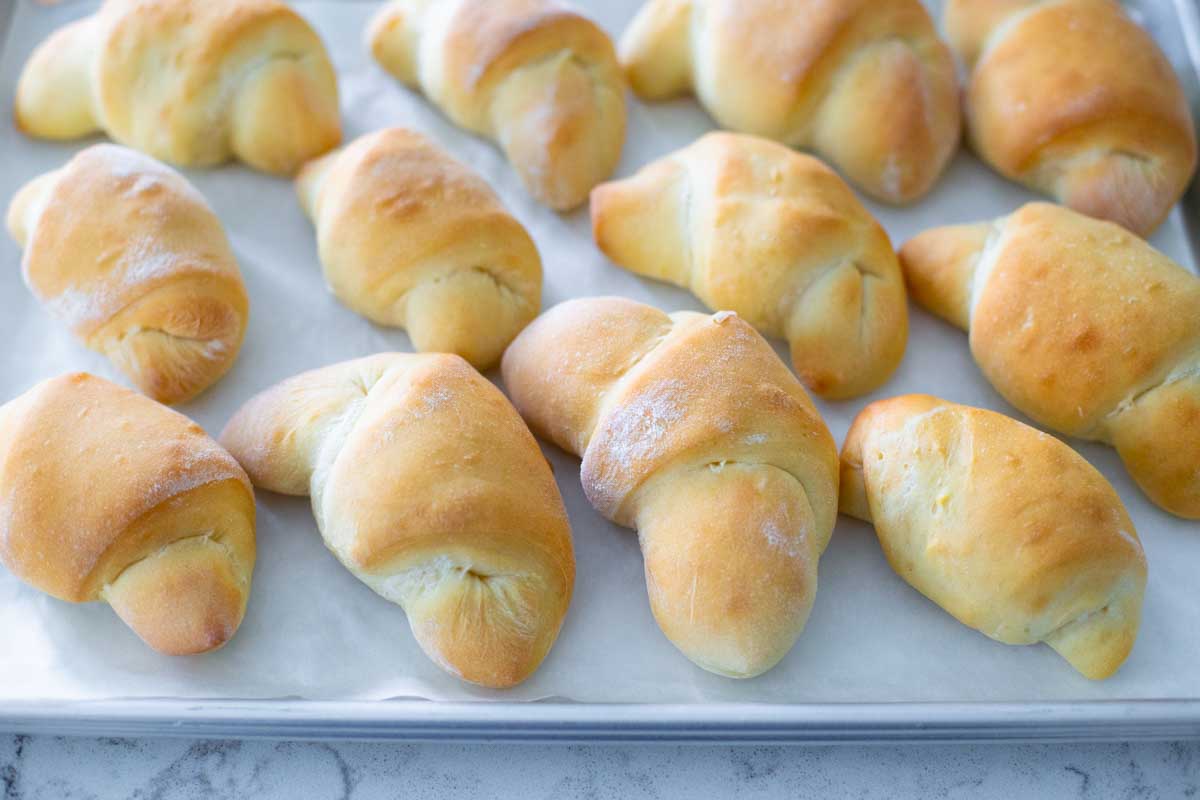 A baking pan is lined with baked crescent rolls.