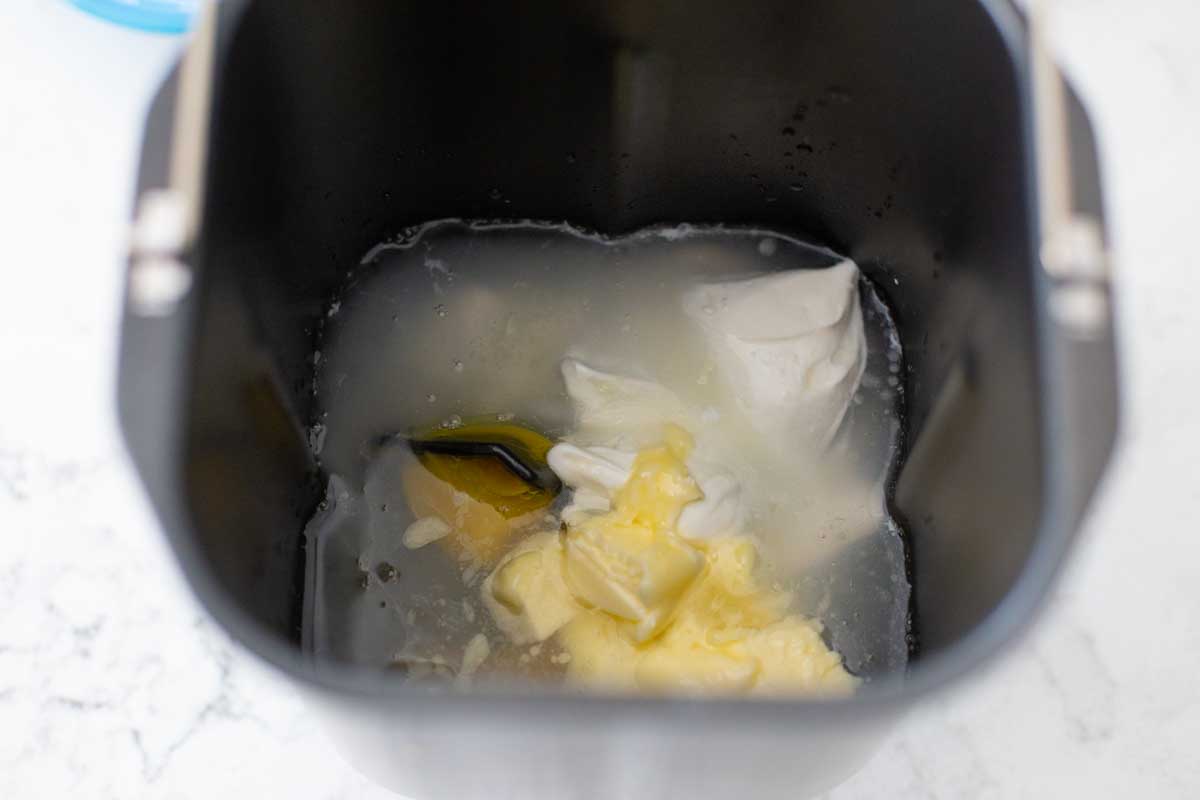 The wet ingredients are added to the bread machine baking pan.