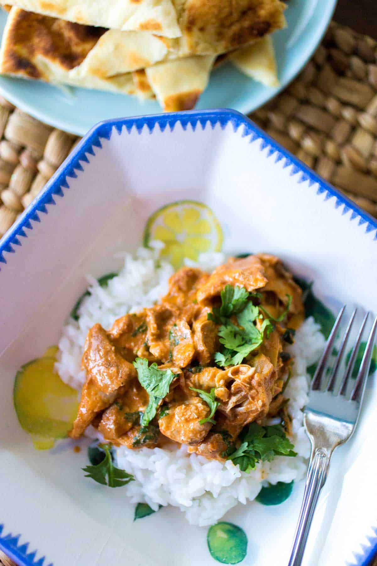 The final dish of butter chicken has been served in a dinner blow with rice and fresh cilantro.